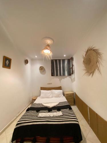a bedroom with a bed with a black and white striped blanket at Bright Wave Surfhouse in Tamraght Ouzdar