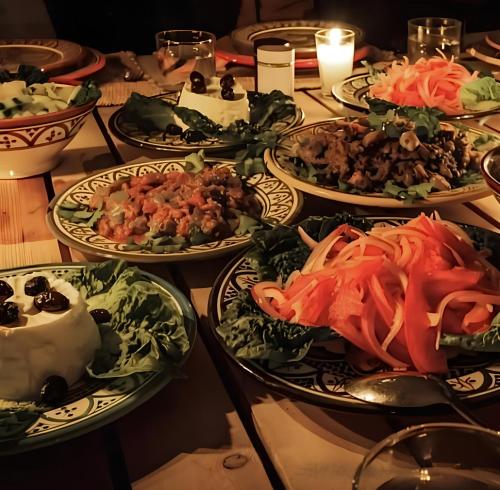 a table with several plates of food on it at Riad Dar Sahara - Panoramic Rooftop in Nkob