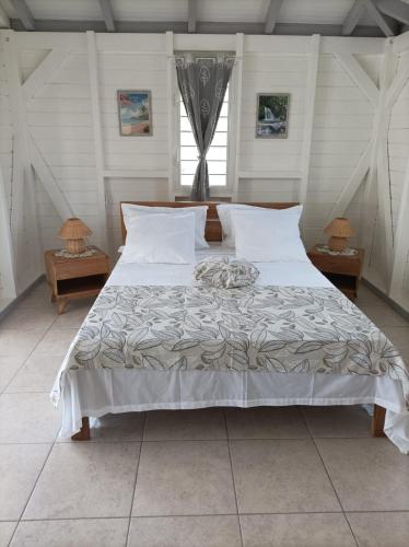 Un dormitorio con una cama grande con sábanas y almohadas blancas. en La Brise Marine, en Petit-Canal