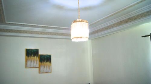 a chandelier hanging in a room with two paintings at City Center Stay - Résidence Omar 1 by ZenStay in Fès