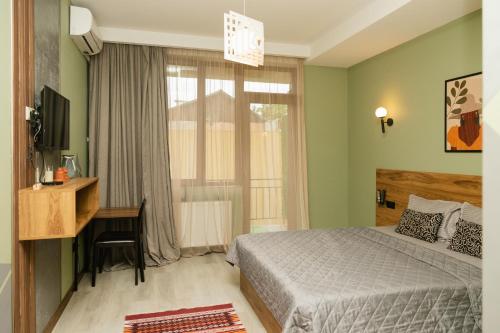 a bedroom with a bed and a desk and a window at Hotel Graif Ti in Tbilisi City
