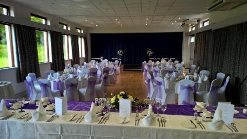 a room full of tables and chairs with purple and white table cloth at Woodland House Hotel in Dumfries