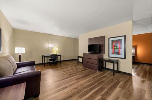 a living room with a couch and a television at Suburban Studios Winston-Salem near Hanes Mall in Winston-Salem