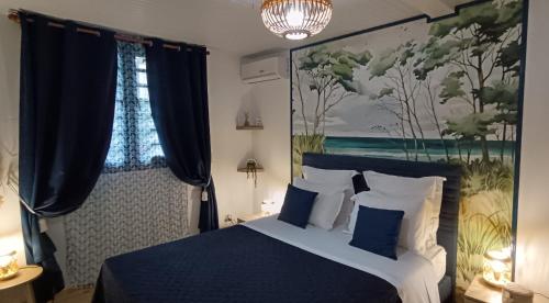 a bedroom with a blue bed with a painting on the wall at Le Voyageur in Sainte-Marie
