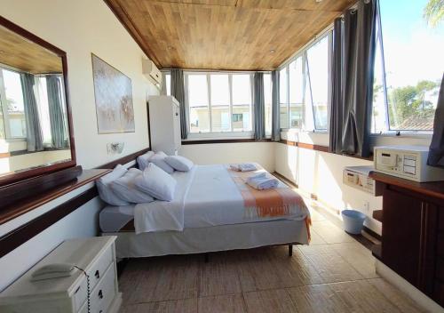 a bedroom with a bed in a room with windows at Hotel Casa Branca in Guarujá