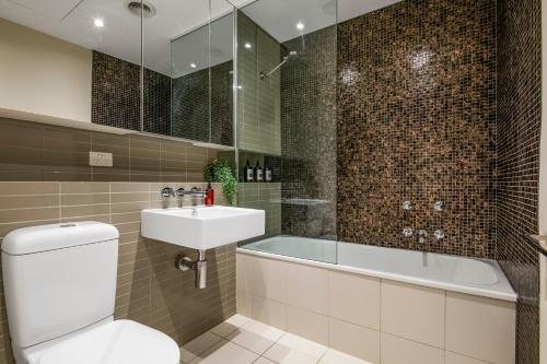 a bathroom with a tub and a toilet and a sink at Spacious City Fringe RetreatPool & Free Parking in Melbourne