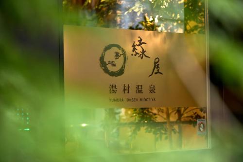 a sign in a window with writing on it at Yumura Onsen MIDORIYA in Shinonsen