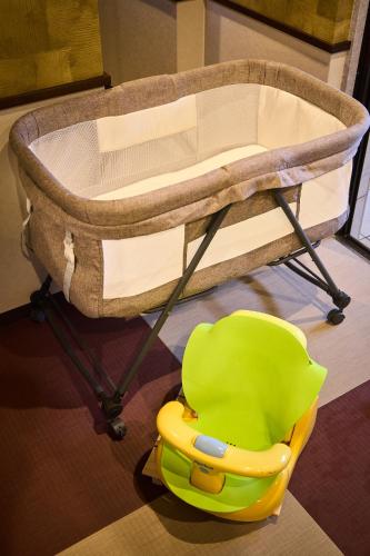 a baby crib with a green chair in a room at Yumura Onsen MIDORIYA in Shinonsen