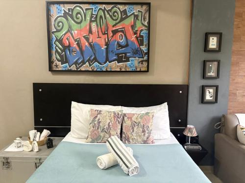 a bedroom with a bed with a painting on the wall at Copacabana - Praia e vista das montanhas in Rio de Janeiro