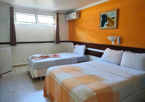 a hotel room with two beds and a window at Hotel Casa Branca in Guarujá