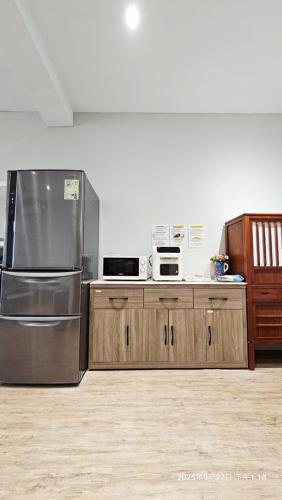 a kitchen with a stainless steel refrigerator and wooden cabinets at 桃園機場羅里輕旅 近桃園竹圍漁港 Rory Hostel in Luzhu