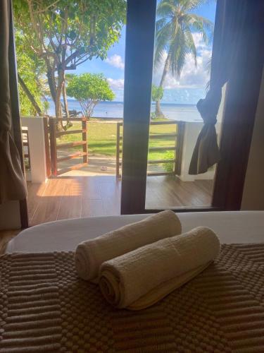two towels on a bed with a view of the ocean at Appartment Bonak peaceful Beachfront Escape with Kitchen and AC in General Luna