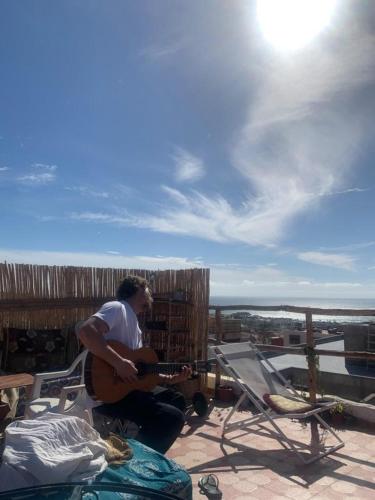 a man is playing a guitar on a patio at Black Pearl surf yoga and skate house in Tamraght Ouzdar