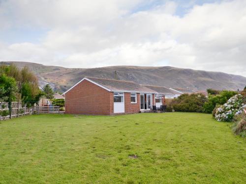 a house with a yard with mountains in the background at Fairlawns in Fairbourne