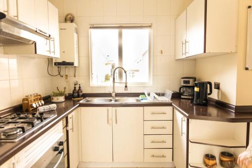 a kitchen with white cabinets and a sink and a window at Casa Magdalena ideal para Familias in Puerto Varas