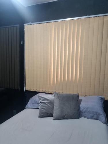 a bed with two pillows in front of a large window at Quarto casal privativo in Cuiabá
