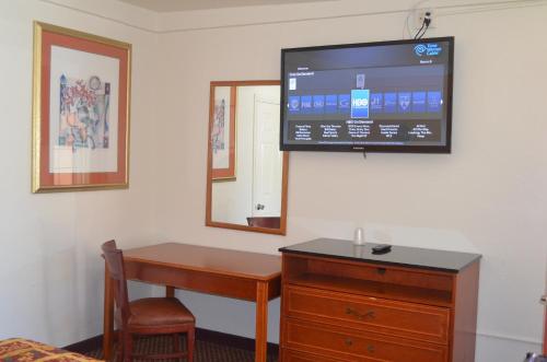 a room with a desk and a tv on the wall at Seaside Inn Motel in Port Hueneme