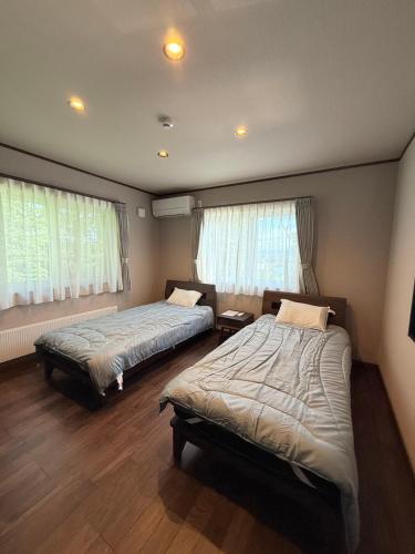 a bedroom with two beds and two windows at furano Hokuseisanso II in Wada
