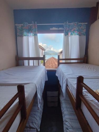 two beds in a room with a window at hostel Boa Onda Trindade in Paraty