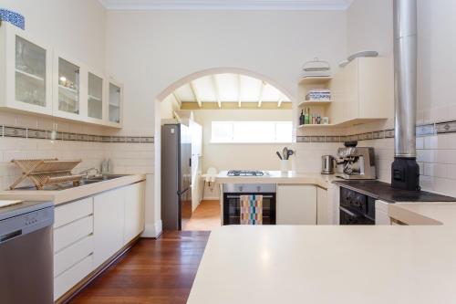 パースにあるFloreat Family Home - With Kids Play Equipmentの白いキャビネットと白いカウンタートップを備えたキッチン