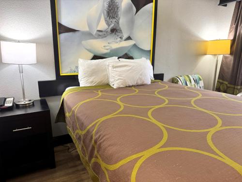 a hotel room with a bed and a painting on the wall at Super 8 by Wyndham Tupelo Airport in Tupelo