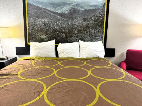 a bedroom with a bed with a painting on the wall at Super 8 by Wyndham Tupelo Airport in Tupelo