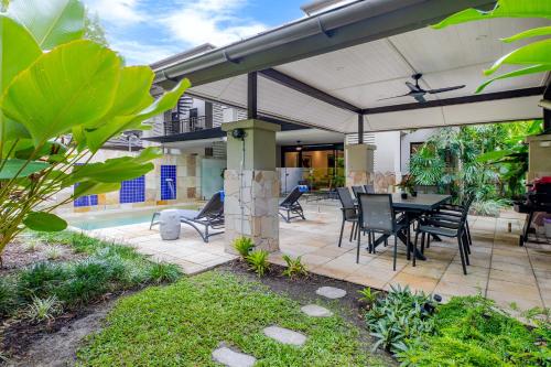 a patio with a table and chairs under an umbrella at SeaEden Port Douglas Apartments in Craiglie