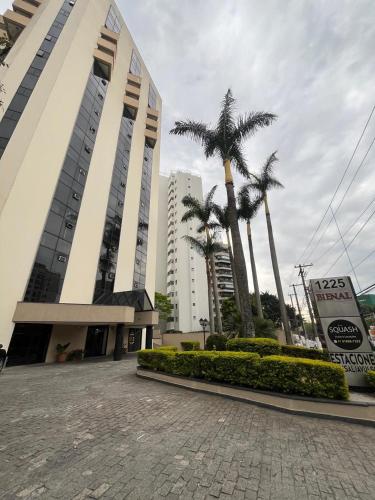 a large building with palm trees in front of it at Hotel Bienal Flat Executivo - UH 304 in Sao Paulo