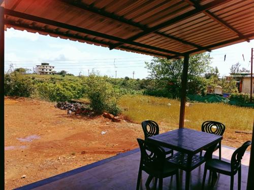 una mesa y sillas en un porche con vistas a un campo en Daksh 3bhk villa wifi call, en Mahabaleshwar