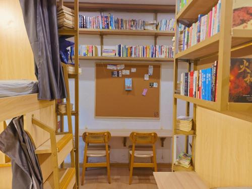 a room with two chairs and a desk and bookshelves at Leshan Qiuye Book House B&B in Leshan