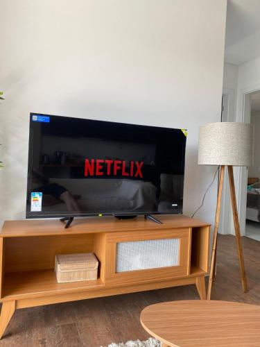 Un televisor sobre un soporte de madera en una sala de estar. en Ap na Brava, en Itajaí