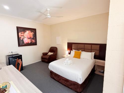a hotel room with a bed and a chair at Coffs Windmill Motel in Coffs Harbour