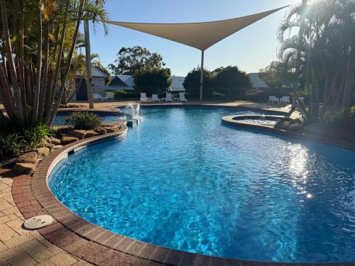 una gran piscina con una sombrilla. en Weerona, en Eaton