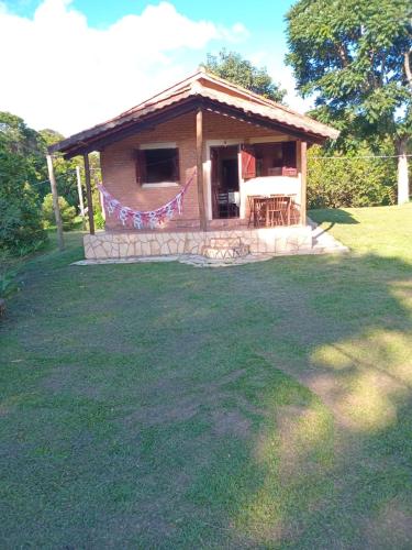 ein kleines Haus auf einem Feld mit einem Rasenplatz in der Unterkunft Chalés e Camping 4 Estações in São Thomé das Letras