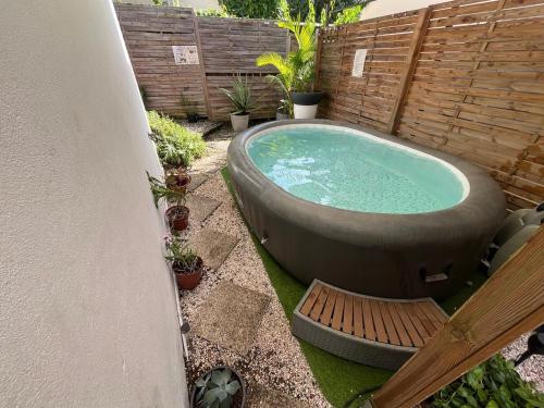 a hot tub in a garden with a wooden fence at Le Calypso - Residence Terre et Truffes in Le Lamentin
