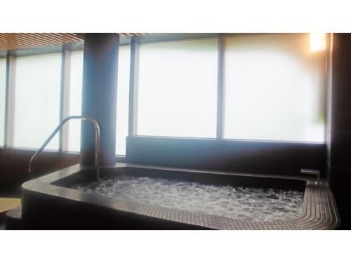 a bath tub with water in it in a room with windows at Skye Niseko - Vacation STAY 30752v in Niseko