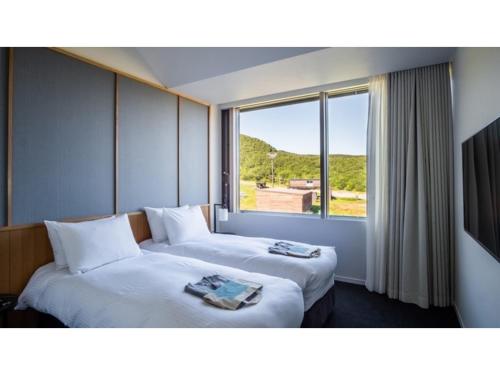 two beds in a room with a large window at Skye Niseko - Vacation STAY 30794v in Niseko