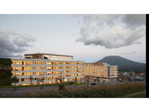a large white building with a mountain in the background at Skye Niseko - Vacation STAY 70563v in Niseko