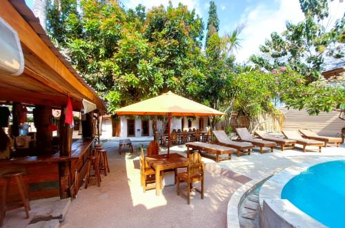 a patio with tables and chairs next to a pool at Jati Village, Party Hostel and Bungalows in Gili Trawangan