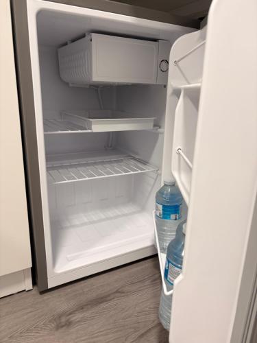 an open refrigerator with two bottles of water in it at Modern En-Suite Double Bedroom in Cardiff with Private Entrance in Cardiff