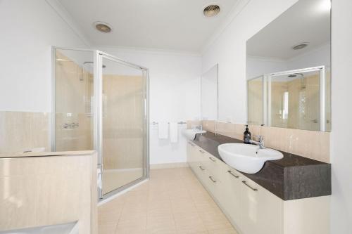a white bathroom with a sink and a shower at 2 Luton in Yarrawonga