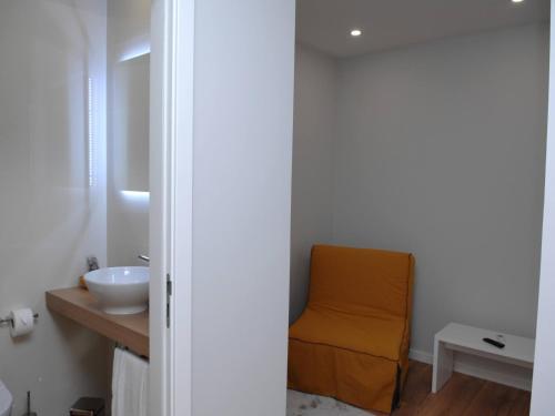 a bathroom with a orange chair next to a sink at Marina Charming House in Figueira da Foz