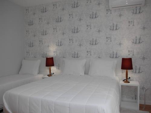a bedroom with a white bed with two lamps at Marina Charming House in Figueira da Foz