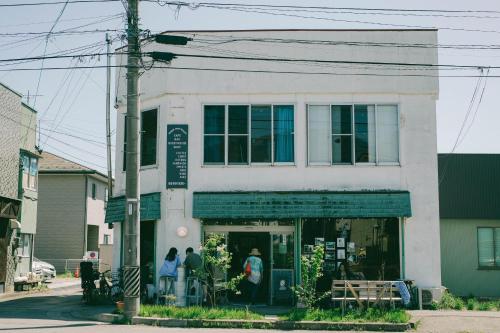 a white building with people standing outside of it at CORNER SHOP Miyota in Miyota