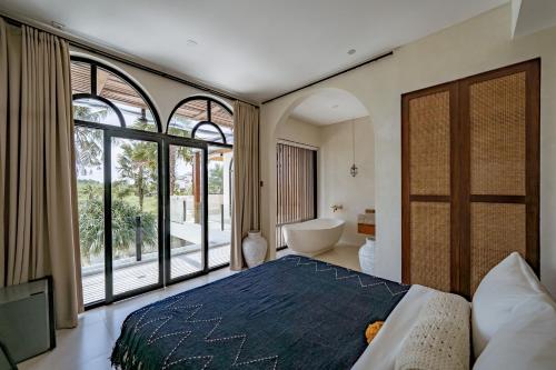 a bedroom with a bed and a tub and a bathroom at Rumah Simba in Munggu