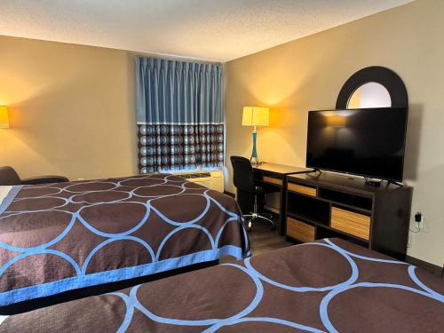 a hotel room with a bed and a flat screen tv at Super 8 by Wyndham Booneville in Booneville