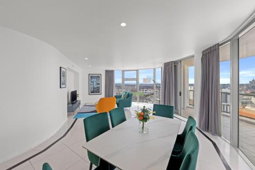 a living room with a table and green chairs at CLLIX Brisbane Central Apartments in Brisbane