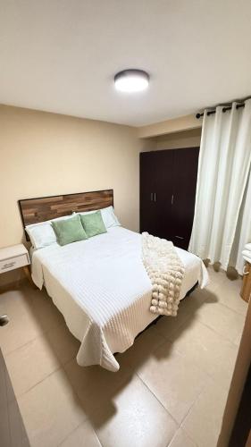 a bedroom with a bed with white sheets and green pillows at Departamento cerca del Zocalo y aeropuerto in Mexico City