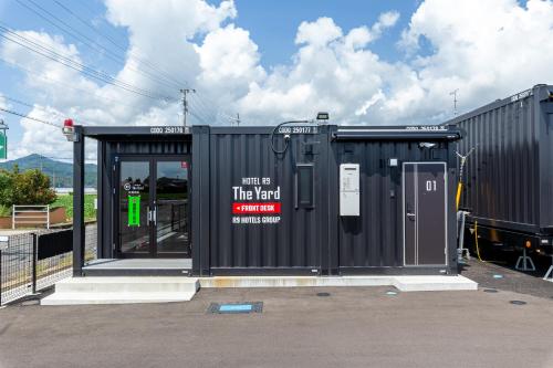 a large black shed with a sign on it at HOTEL R9 The Yard Sagakashima in Kashima