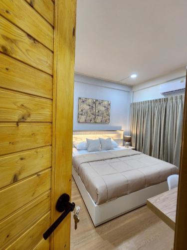 a bedroom with a bed and a wooden door at Cozy KingsizeBed เจริญนคร in Ban Hua Phrong